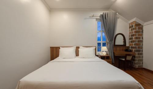 a bedroom with a white bed and a window at Le Soleil Boutique Hotel in Da Lat