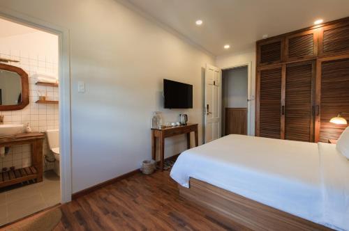 a bedroom with a large white bed and a bathroom at Le Soleil Boutique Hotel in Da Lat