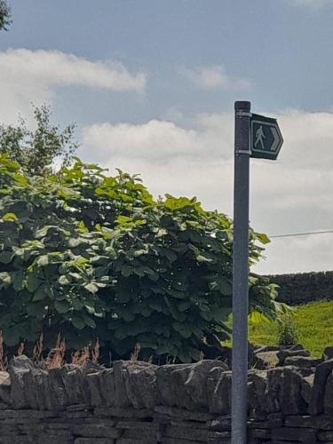 a street sign on a pole in front of a hedge at south view farm cottage 1 Bed in Bradford
