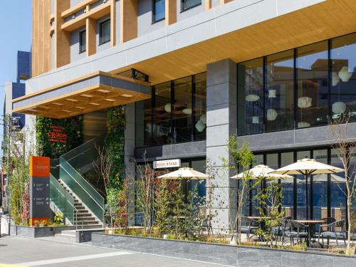 a building with tables and umbrellas in front of it at Nishitetsu Hotel Croom Hakata Gion Kushida Shrine in Fukuoka