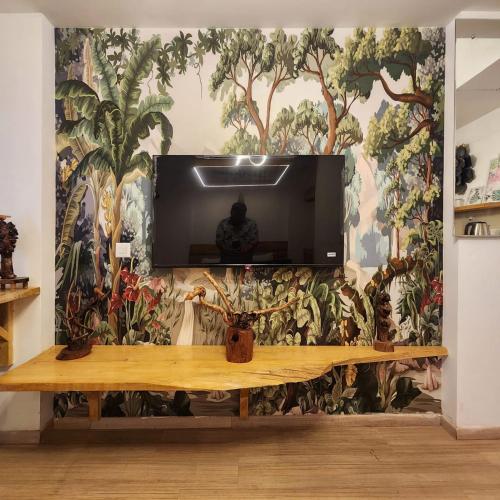 a tv on a wall with a mural of plants at The Nest Lucknow in Lucknow