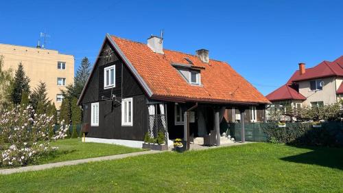 a black house with an orange roof on a yard at Domek Mazury Pisz in Pisz