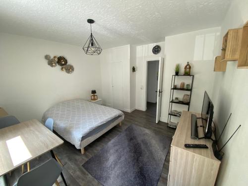 une chambre avec un lit et un bureau avec une télévision dans l'établissement Bel appartement avec parking et terrasse plein sud, au Havre