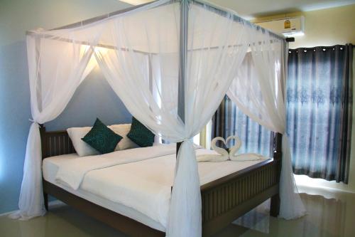 a bedroom with a canopy bed with white curtains at Blue House Sukhothai in Sukhothai