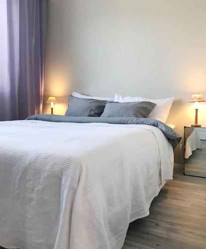 a white bed in a bedroom with two lamps at Aurora Home Kivistö 1-bedroom apartment for up to 8 near Helsinki Vantaa Airport and Helsinki city center in Vantaa