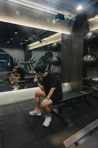 a man sitting on a bench in a gym at Art Mai Gallery Nimman Hotel Chiang Mai in Chiang Mai