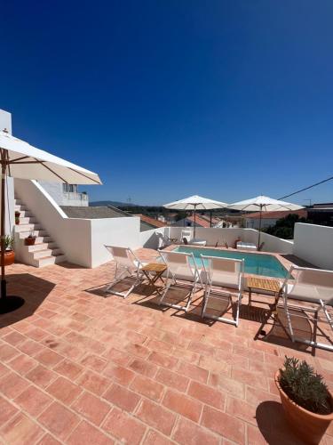 une terrasse avec une table, des chaises et des parasols dans l'établissement Guesthouse Casa Felicia, à Montes de Alvor