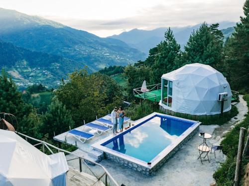 two people standing next to a house with a swimming pool at Paradise Inn in Batumi