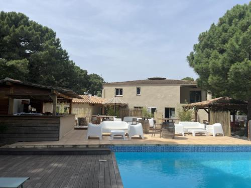 une terrasse avec des chaises blanches et une piscine dans l'établissement Fiori di Cala Rossa résidence hôtelière, à Lecci