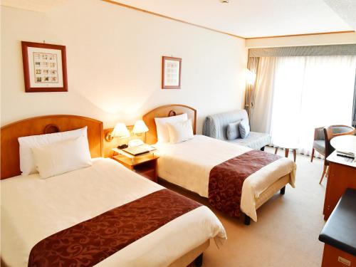 a hotel room with two beds and a chair at Hotel BELLMARE ホテルベルマーレ in Maizuru