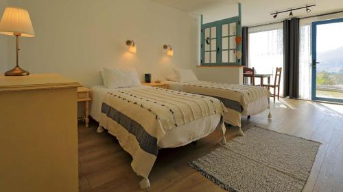 a bedroom with two beds and a desk and a window at Quinta Ecológica da Peneda Agroturismo by Peneda ecofarm in Arcos de Valdevez