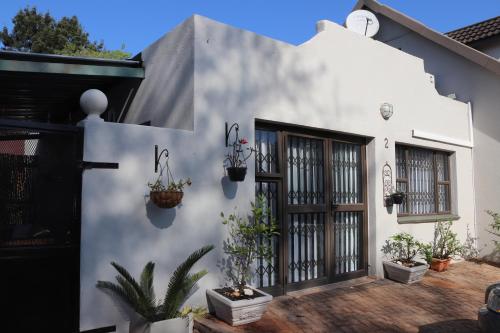 a white house with potted plants on the side of it at Giraffe's Rest, Self Catering Studio Apartment in White River