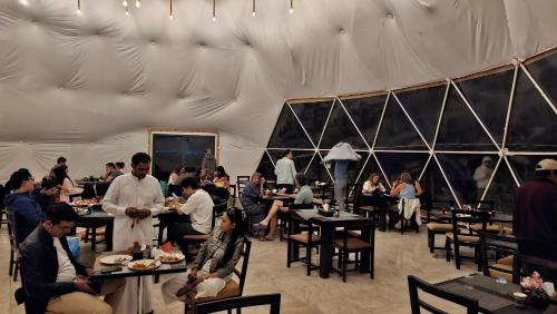 a group of people sitting at tables in a restaurant at Darien Luxury Camp in Wadi Rum