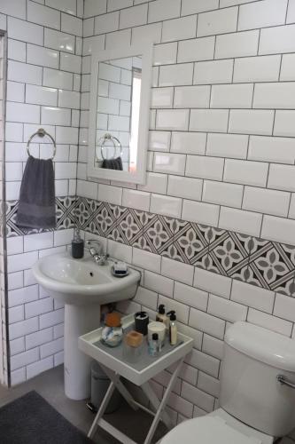 a bathroom with a sink and a toilet and a mirror at Giraffe's Rest, Self Catering Studio Apartment in White River