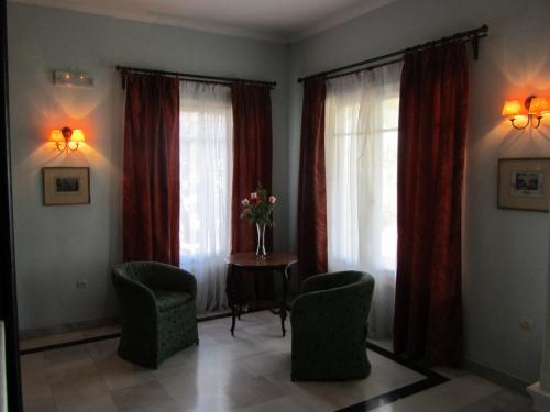 a living room with two windows and chairs and a table at Levant Hotel in Pelekas