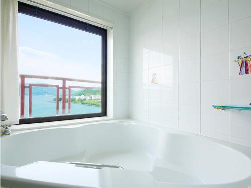 a bathroom with a white tub and a window at Hotel BELLMARE ホテルベルマーレ in Maizuru