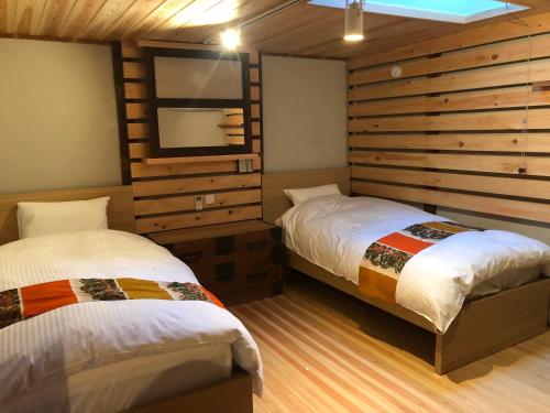 two beds in a room with wooden walls at 銅の夢 in Ōmama