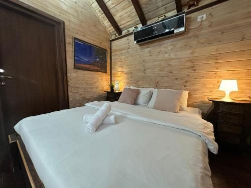 a bedroom with a large bed with white sheets and pillows at בורקאי - בקתות פיליפיניות עם בריכה פרטית in Bruchim Qela' Alon