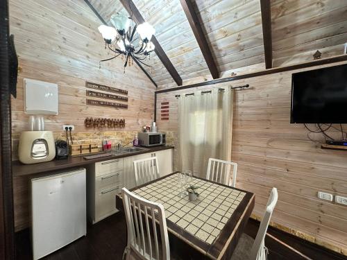 a kitchen with a table and chairs and a television at בורקאי - בקתות פיליפיניות עם בריכה פרטית in Bruchim Qela' Alon