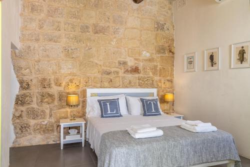 a bedroom with a bed and a stone wall at Lemon Tree Relais by CX Collection in Żabbar