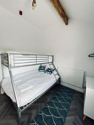 a bedroom with a bunk bed with white sheets and a rug at The Windmill, Lytham St Annes in Saint Annes on the Sea