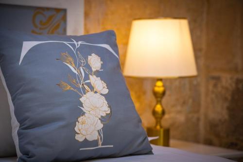 a blue pillow with a flower on it next to a lamp at Lemon Tree Relais by CX Collection in Żabbar