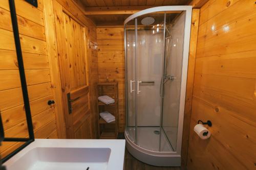 a shower in a wooden bathroom with a tub at Tiny house Aria in Makarska
