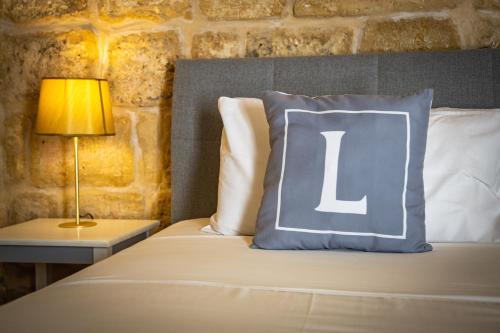 a bed with a pillow with the letter l on it at Lemon Tree Relais by CX Collection in Żabbar