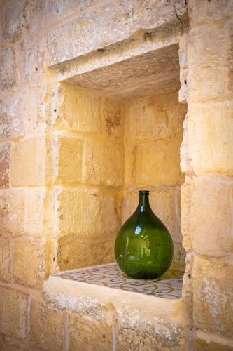 a green vase sitting on a shelf in a brick wall at Lemon Tree Relais by CX Collection in Żabbar