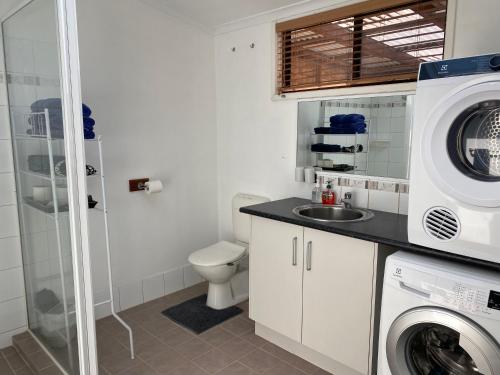 a bathroom with a sink and a washing machine at Sabai accommodation in Dongara
