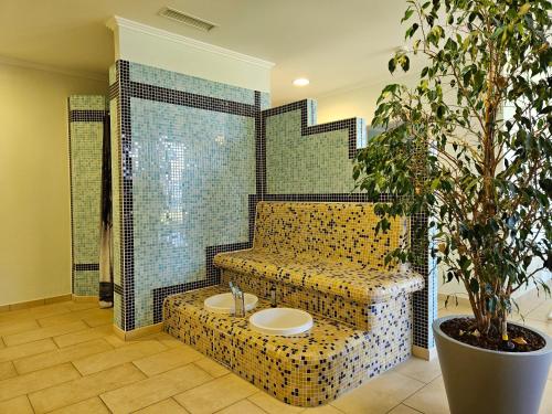 a bathroom with a couch with a sink and a plant at Seehotel Hubertus in Schluchsee