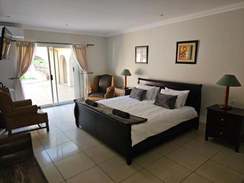 une chambre avec un grand lit et une chaise dans l'établissement Ridge Guest House, à Durban