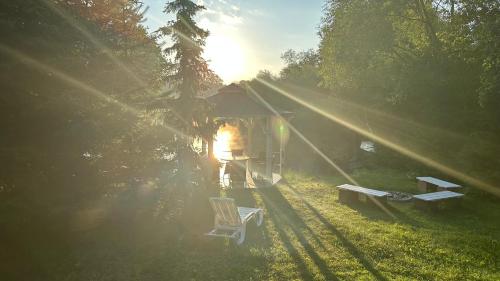 a house with the sun shining through the trees at Mazurskie Siedlisko Langen in Mrągowo
