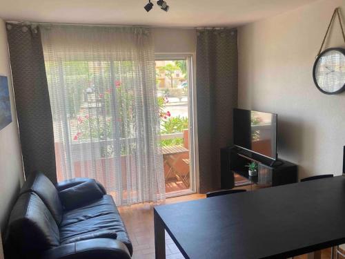 - un salon avec une chaise, une table et une fenêtre dans l'établissement Beau T3 - plain pied - terrasses, à Port-la-Nouvelle