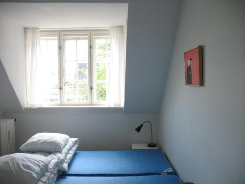 a bedroom with a blue bed and a window at Thurø Kro B&B in Svendborg