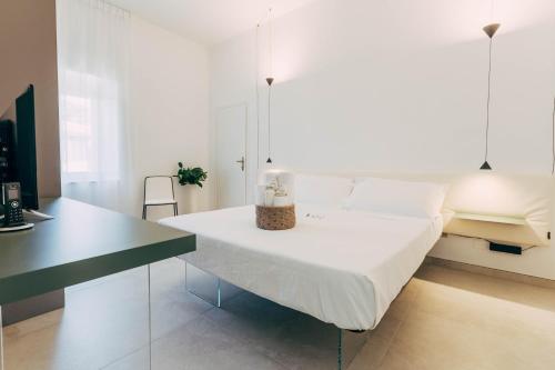 a white bedroom with a bed and a desk at Villa Giulietta Hotel in Castiglioncello