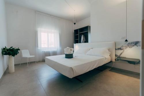 una camera bianca con un grande letto e una sedia di Villa Giulietta Hotel a Castiglioncello