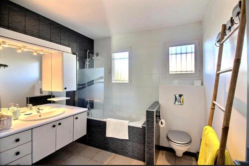 a bathroom with a tub and a sink and a toilet at Villa Signado in Portiragnes