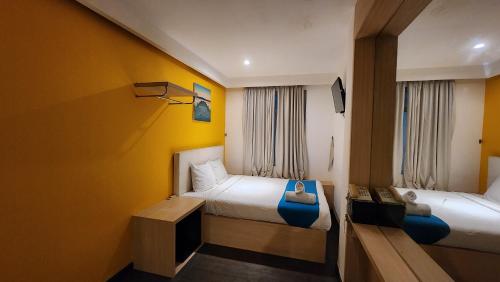 a hotel room with two beds and a tv at Kimono Spa Hotel in Kuta