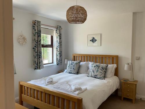 a bedroom with a bed with white sheets and a window at Sunnyside Cottage in Crantock