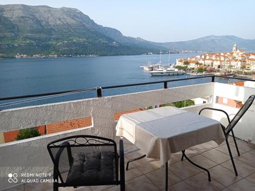 een tafel en stoelen op een balkon met uitzicht op een waterlichaam bij Apartments Panorama in Korčula