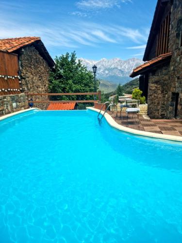 una gran piscina azul con montañas en el fondo en La Casa de las Chimeneas, en Tudes