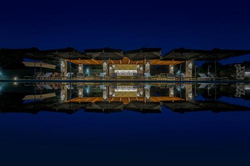 a house with a reflection in the water at night at Mint Retreat Suites in Kalandra