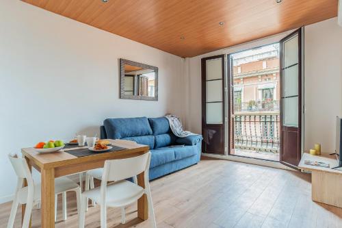 AB Nou de la Rambla في برشلونة: غرفة معيشة مع أريكة زرقاء وطاولة