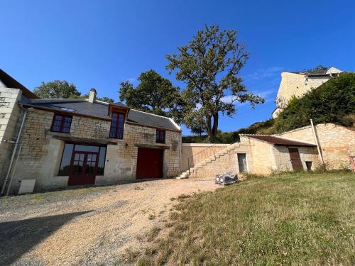 une ancienne maison en pierre avec une allée et un arbre dans l'établissement Gîte du château, à Thizay