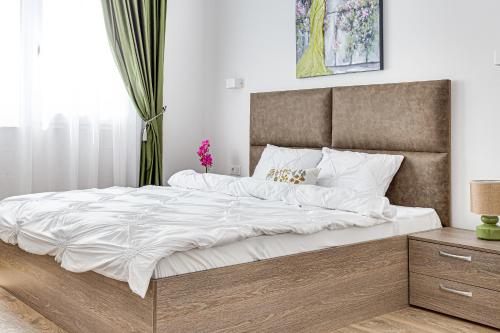 a bedroom with a large bed with white sheets at ARI Olive Apartment near Atrium & AFI Mall in Arad