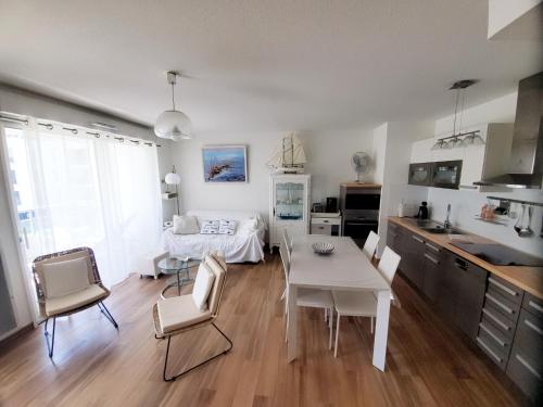 une cuisine et un salon avec une table et des chaises blanches dans l'établissement Le Carré des Sens, à La Rochelle