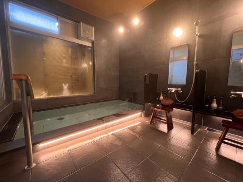 a bathroom with a bath tub with a window at Oyado Ikegami in Uozu