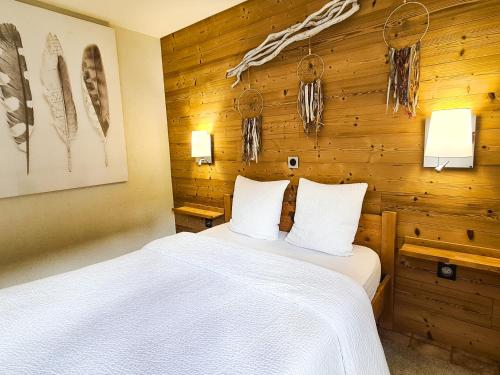 a bedroom with a white bed in a wooden wall at Appt les Granges - Vue montagne et village, Centre la Clusaz - AravisTour in La Clusaz
