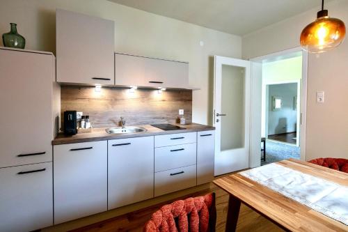 a kitchen with white cabinets and a wooden table at Winzerhaus Rose in Wald in der Weststeiermark